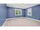 Blue bedroom featuring two windows, trim, and carpeted floors at 1230 Sykes Rd, Spring Hope, NC 27882