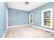 Empty bedroom with light blue walls, carpeted floors, and natural light from multiple windows at 1230 Sykes Rd, Spring Hope, NC 27882