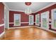Formal dining room with hardwood floors, red walls, white trim, and a crystal chandelier at 1230 Sykes Rd, Spring Hope, NC 27882