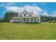 Expansive farmhouse with a charming wrap-around porch and lush green lawn on a sunny day at 1230 Sykes Rd, Spring Hope, NC 27882