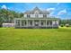 Spacious farmhouse with wrap-around porch, set on a sprawling green lawn under a bright sky at 1230 Sykes Rd, Spring Hope, NC 27882