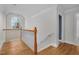Upstairs hallway featuring hardwood floors, white wainscotting, and a view of a chandelier at 1230 Sykes Rd, Spring Hope, NC 27882