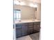 Bathroom with dual sink vanity, large mirror, grey cabinets, and neutral walls at 1402 Southpoint Trl, Durham, NC 27713