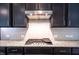 Close-up of a kitchen cooktop featuring granite countertops and a stylish white subway tile backsplash at 1402 Southpoint Trl, Durham, NC 27713
