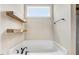 Bright bathroom features a soaking tub under a window with two floating wooden shelves at 147 Everwood Dr, Four Oaks, NC 27524