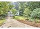 Home's front yard showcases the home and driveway with garden and lush trees at 1516 Edgevale Rd, Durham, NC 27701