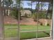 View of a backyard featuring a grassy area, trees, and other greenery, as seen through a screened-in porch at 1524 Chirping Bird Ct, Cary, NC 27519