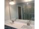 Elegant bathroom featuring double sinks, a large mirror, quartz countertops, and a tiled shower with glass door at 1524 Chirping Bird Ct, Cary, NC 27519