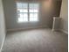 Well-lit bedroom featuring a bright window, neutral walls, and cozy carpeting at 1524 Chirping Bird Ct, Cary, NC 27519
