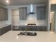Modern kitchen with stainless steel appliances, range hood, gray cabinets, and white countertops at 1524 Chirping Bird Ct, Cary, NC 27519