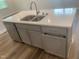 Kitchen island with stainless steel sink, white countertop, gray cabinets and drawers, and stainless steel dishwasher at 1524 Chirping Bird Ct, Cary, NC 27519