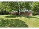The large grassy backyard leads up to the house and deck, with mature trees at 1601 Redmond Dr, Durham, NC 27712