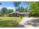 Charming brick home featuring a manicured lawn, mature trees, and a welcoming front porch at 1601 Redmond Dr, Durham, NC 27712