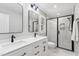 Bright bathroom boasts dual sinks, black fixtures, marble tile, and glass enclosed shower at 1609 Falls Ct, Raleigh, NC 27615