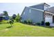 Well-maintained backyard featuring lush lawn, garden beds, and the exterior of the home with stone accents at 1918 Morning Fog Dr, Fuquay Varina, NC 27526