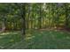 Spacious backyard with lush grass, mature trees, and a stone fire pit for outdoor enjoyment at 2012 Silverleaf Dr, Youngsville, NC 27596