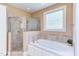Well-lit bathroom featuring a tiled shower, soaking tub, and storage cabinets at 2012 Silverleaf Dr, Youngsville, NC 27596