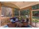 Relaxing screened porch featuring wicker furniture, string lights, and scenic backyard views of the lush landscaping at 2012 Silverleaf Dr, Youngsville, NC 27596
