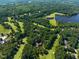 Expansive aerial view featuring the golf course, houses nestled in lush greenery, and a scenic lake with a dam at 2602 Vintage Hill Ct, Durham, NC 27712