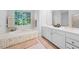 Bathroom has a soaking tub under a large window, and a double vanity with white cabinets at 2602 Vintage Hill Ct, Durham, NC 27712