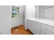 Well-lit bathroom features a white vanity, a large mirror, and hardwood floors at 2602 Vintage Hill Ct, Durham, NC 27712