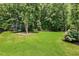 Expansive backyard featuring lush green grass, mature trees, and a trampoline, perfect for outdoor activities and relaxation at 2716 Willow Rock Ln, Apex, NC 27523