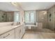 Relaxing bathroom featuring a tub and shower with a neutral tone tile and double sink vanity with ample lighting at 2716 Willow Rock Ln, Apex, NC 27523
