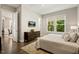 Comfortable bedroom with hardwood floors, a neutral color scheme, and a view of the lush greenery outside at 2716 Willow Rock Ln, Apex, NC 27523