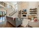 Bright living room with a stone fireplace, wood floors, floating shelves, high ceilings and staircase to the second floor at 2716 Willow Rock Ln, Apex, NC 27523
