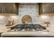 Close up of a stainless steel Kitchen Aid gas cooktop with white subway tile backsplash and wooden decor at 2716 Willow Rock Ln, Apex, NC 27523