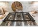 Close up of a stainless steel Kitchen Aid gas cooktop with white marble backsplash and wooden boards at 2716 Willow Rock Ln, Apex, NC 27523