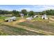 Aerial view of a rural farm featuring multiple structures, equipment, and cultivated fields under a blue sky at 2856 Gwyn Rd, Elon, NC 27244