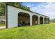 View of a white, metal, multiple bay outbuilding with various farm equipment stored inside at 2856 Gwyn Rd, Elon, NC 27244