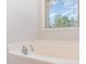 Large white soaking tub with chrome faucet and a bright window view at 3036 Landing Falls Ln, Raleigh, NC 27616