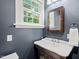 Bathroom featuring a classic sink, mirror, light fixtures, and a window with lots of natural light at 304 Polk St, Raleigh, NC 27604
