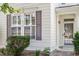 Close up of a front exterior with white siding and gray shutters surrounding large windows near a front door at 3147 Rapid Falls Rd, Cary, NC 27519