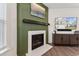 Close-up of modern fireplace with white surround and a green accent wall with artwork at 3194 Retama Run, New Hill, NC 27562