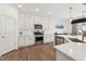 Well-lit kitchen boasts stainless steel appliances, white cabinets and gorgeous wood flooring at 3194 Retama Run, New Hill, NC 27562