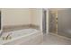 A bathroom showcasing a soaking tub and glass-enclosed shower with a view of the closet at 402 Bridewell Ct, Cary, NC 27518