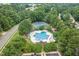 Aerial shot of a community pool with lounge chairs, trees, a tennis court and parking at 402 Bridewell Ct, Cary, NC 27518