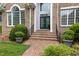 Charming front entrance with brick steps, lush greenery, and a security system sign at 402 Bridewell Ct, Cary, NC 27518