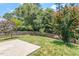 Large, well-manicured backyard featuring a brick-paved patio, lush lawn, mature trees, and a wooden fence at 404 Ascott Way, Durham, NC 27713