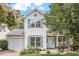 Charming two-story home with a white exterior, blue shutters, a well-manicured lawn, and mature landscaping at 404 Ascott Way, Durham, NC 27713