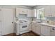 Well-lit kitchen featuring white cabinets, gas range, and stainless steel dishwasher at 404 Ascott Way, Durham, NC 27713