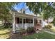 Inviting red brick house featuring a cozy front porch with white railing and lush landscaping at 412 Coggeshall St, Oxford, NC 27565