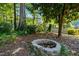 Backyard features a stone fire pit, surrounded by mature trees and lush landscaping at 4151 Deep Wood Cir, Durham, NC 27707