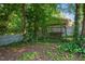 Backyard with a swing in a shaded area, surrounded by lush greenery and a white picket fence at 4151 Deep Wood Cir, Durham, NC 27707