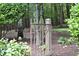 An ornate metal gate leads to garden area with mature trees, lush landscaping and privacy at 4905 Ivercroft Pl, Fuquay Varina, NC 27526