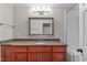 Bathroom with cherry-stained vanity, granite countertop, decorative mirror and shower with glass door at 4905 Ivercroft Pl, Fuquay Varina, NC 27526