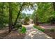 Long driveway leading to brick home featuring mature trees, lush landscaping and three car garage at 4905 Ivercroft Pl, Fuquay Varina, NC 27526